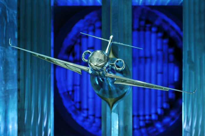 Silver model airplane in wind tunnel.