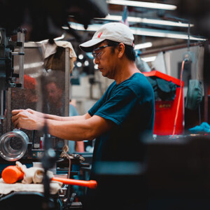 Factory worker adjusting milling machine with tools