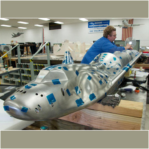 Large polished metal aircraft mockup in workshop