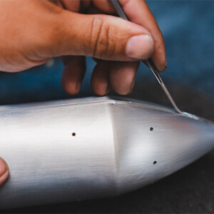Hand detailing aluminum aircraft nose using tweezers