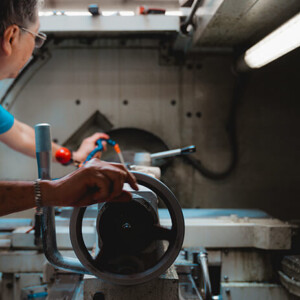Technician turning lathe handwheel inside workshop